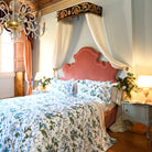 Front view of Fantasia floral printed duvet cover on bed with coral headboard and white cotton layering