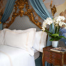Side view of golden cream embroidered duvet set with white orchid and antique nightstand