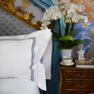 Close-up of navy embroidery on Oxford pillow sham by Villa Cotton, placed in luxury Italian bedroom with floral decor