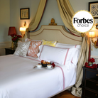 Luxurious white duvet cover set with ruby red embroidery in opulent bedroom setting, endorsed by Forbes