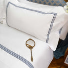 Detailed view of Villa Cotton navy embroidered pillowcase on long-staple cotton bedding with antique mirror on bed