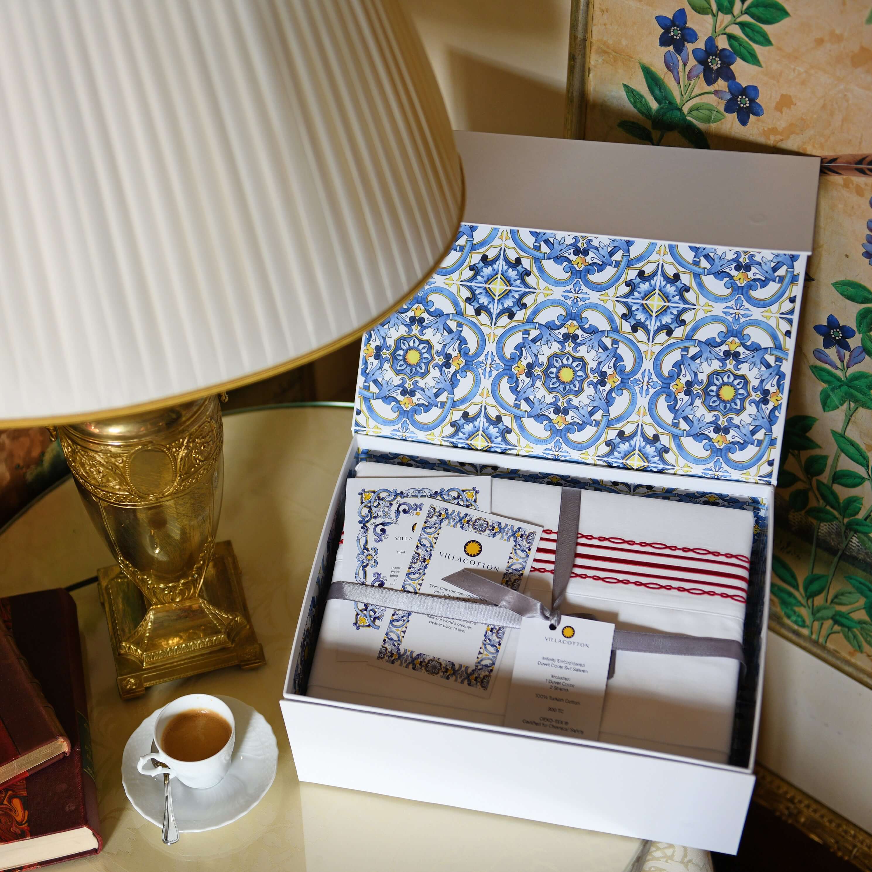 Gift box of ruby red embroidered duvet cover set with branded inserts and Italian espresso