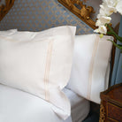 Close-up of Oxford shams with golden embroidery on white cotton background