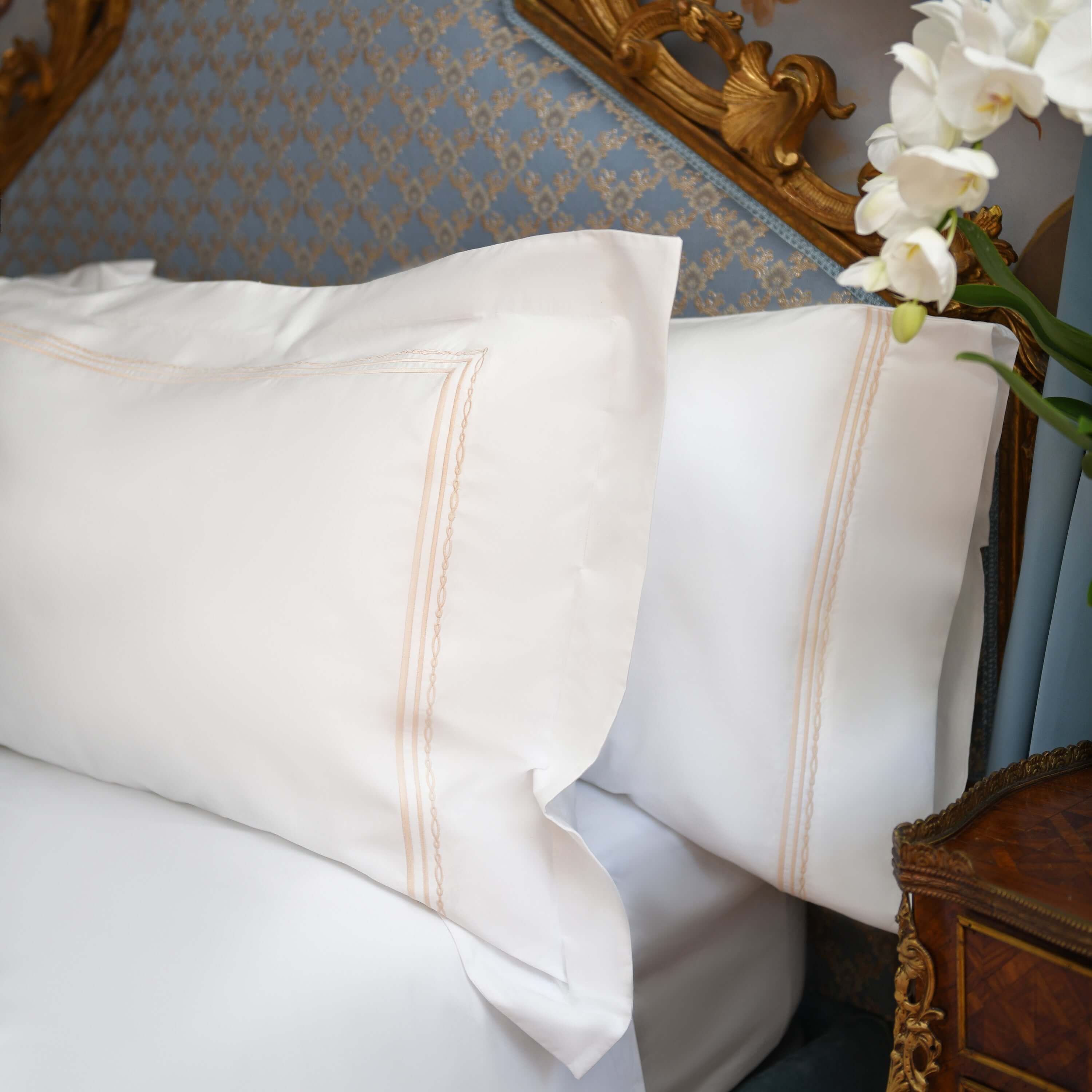 Close-up of Oxford shams with golden embroidery on white cotton background