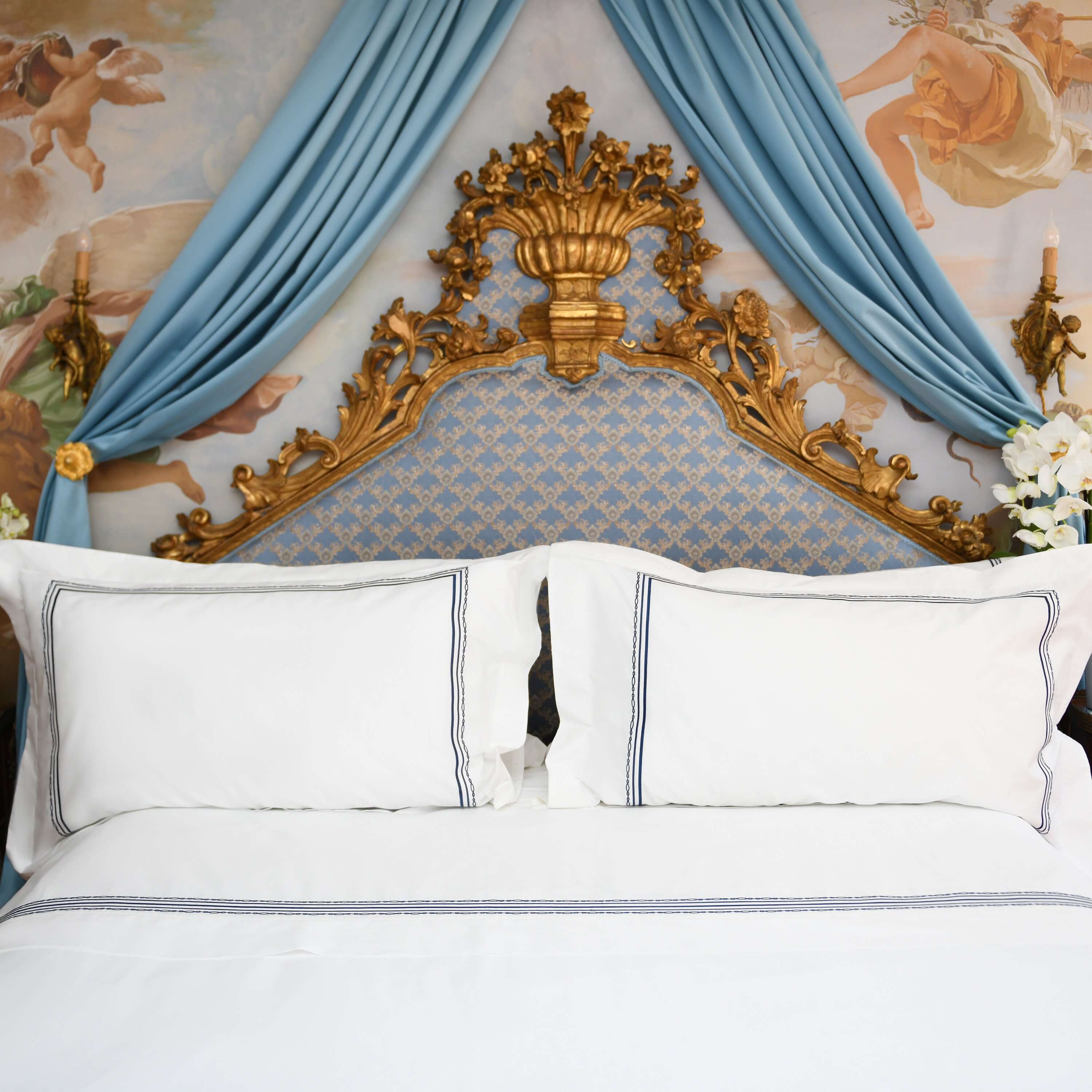 Front view of luxury hotel-style bed with Villa Cotton navy embroidered duvet cover and Oxford pillow shams