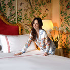 Model making bed with ruby red embroidered duvet cover set in luxury hotel-style bedroom