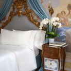 White embroidered bedding with golden details next to Villa Cotton branded box and books
